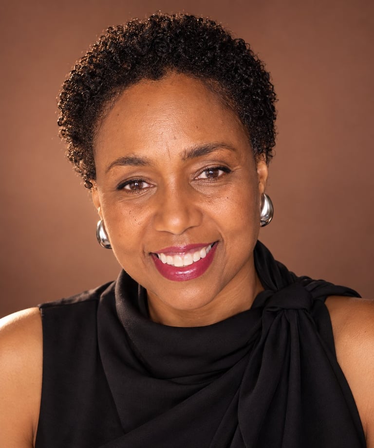 Professional headshot of a woman with short curly dark hair, wearing a black sleeveless top, smiling at camera against brown background
